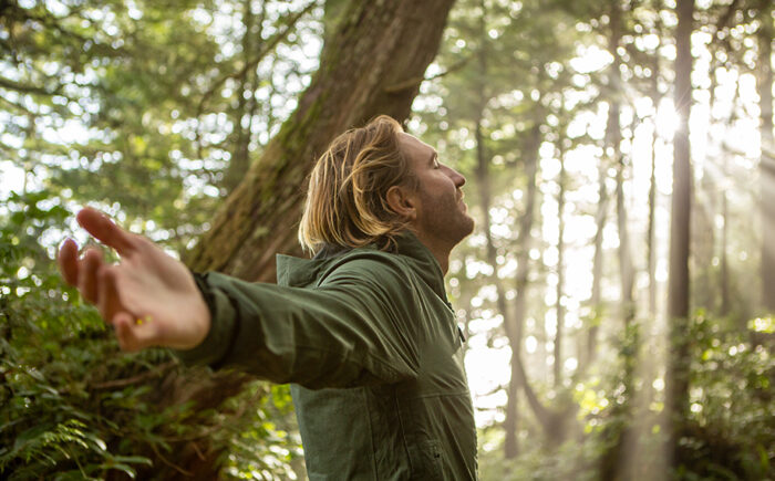 Junger man geniesst die Natur im Wald